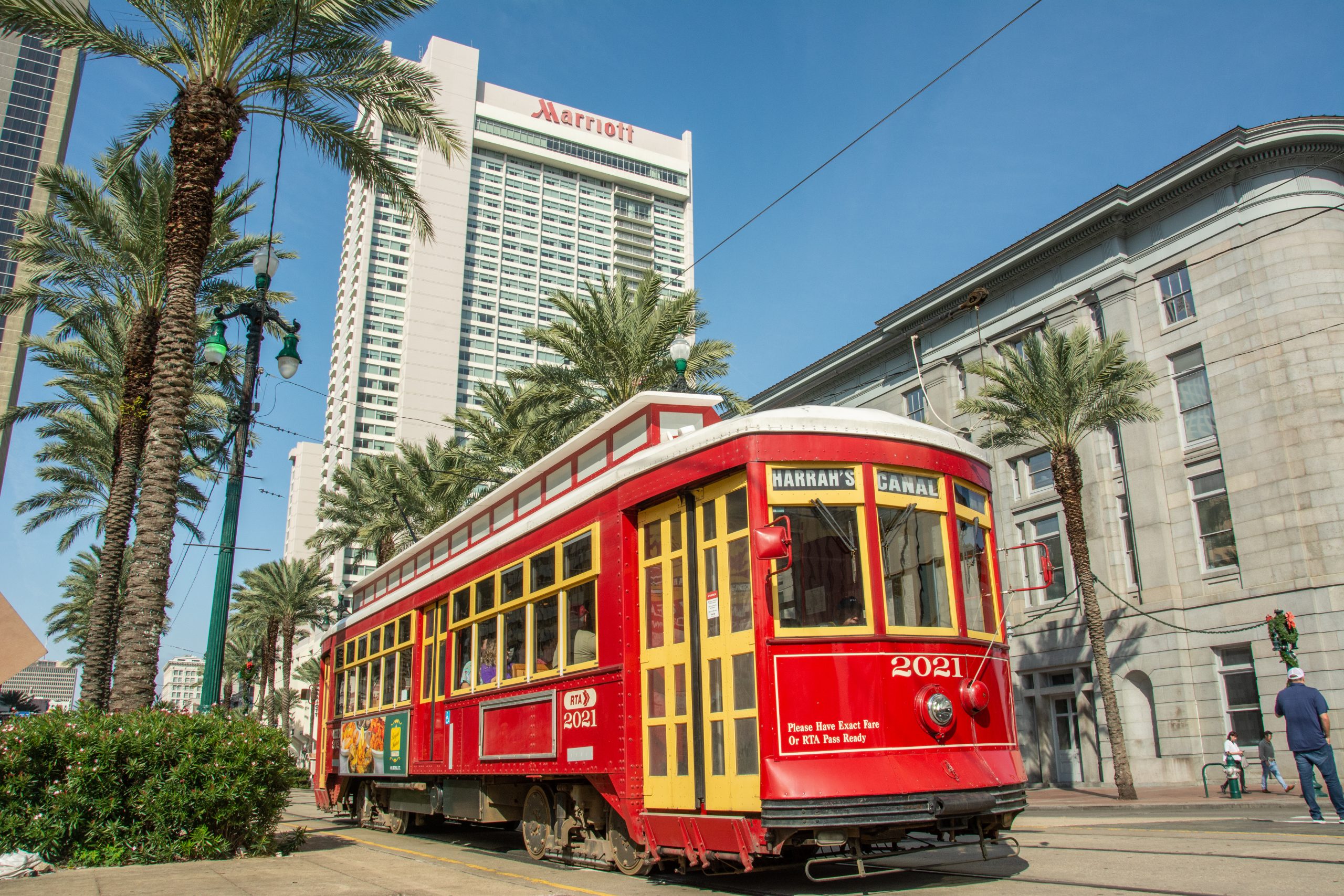 New Orleans, USA – December 3, 2022 - Red old streetcar on Canal Street and palm tree alley in New Orleans, LA